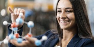 Junge lachende Frau mit einem Atommodell in den Händen